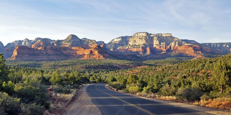 Red rock cliffs and mesas rising above green juniper woodland, seen from Dry Creek Road in west Sedona, Arizona
